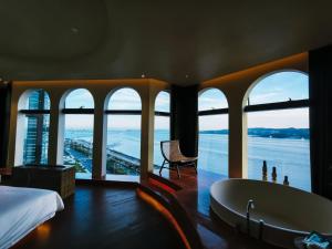 a bedroom with a tub and a view of the water at Shanheli Mediterranean Seaside Resort Homestay East Coast Branch in Ma Yu