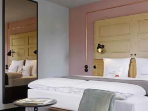 a bedroom with two beds and a mirror at 25hours Hotel Altes Hafenamt in Hamburg