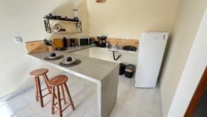 a kitchen with a white refrigerator and two stools at pipa paradise lofts in Tibau do Sul
