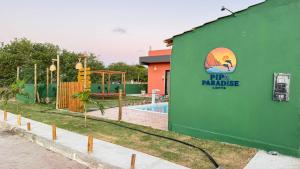 a green building with a sign on it next to a pool at pipa paradise lofts in Tibau do Sul