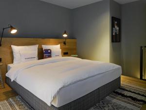 a bedroom with a large bed with white sheets and pillows at 25hours Hotel The Trip in Frankfurt/Main +49 photos