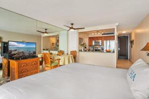 a bedroom with a large white bed and a kitchen at Mahana 713 · MA 713 Luxury OceanFront Studio in Kahana