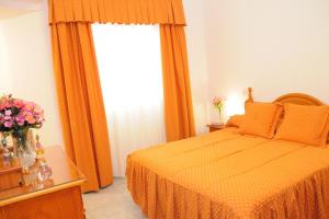 a bedroom with a bed with orange curtains and a window at Amplio Apartamento in Vecindario +3 photos