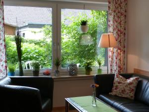 ein Wohnzimmer mit einem Sofa und einem Fenster mit Topfpflanzen in der Unterkunft Ferienwohnung Lerchenweg in Möhnesee