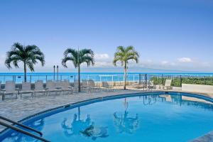 a swimming pool with palm trees and the ocean at Hololani A204 in Kahana