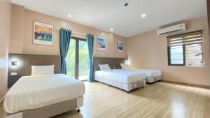 Un dormitorio con dos camas y una ventana. en Catba Paddy House, en Cat Ba