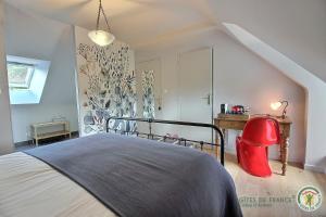 a bedroom with a bed with a red chair in it at La metairie in Plédèliac