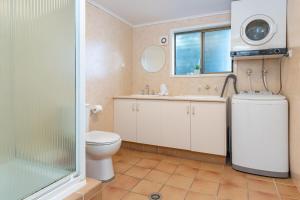 a bathroom with a toilet and a sink and a window at Reflections in Smiths Lake