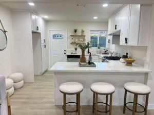 a kitchen with white cabinets and bar stools at Flora in Ontario