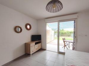 a living room with a television and a table and a sliding glass door at Kampagn Jacuzzi - Rémire Wifi et climatisation in Bourda