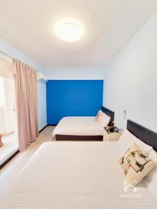 a bedroom with two beds and a blue wall at 芳心蘭厝民宿 in Wujie