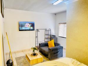 a living room with a chair and a tv on the wall at Genza Guesthouse in Pretoria in Pretoria