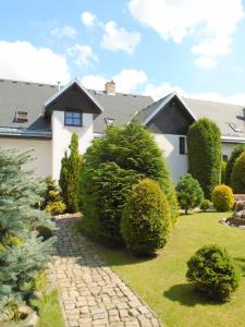 Wellness Penzion Lázně Jablonec في يابلونيتس ناد نيسو: منزل به حديقة بها شجيرات وممشى