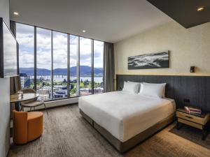 a hotel room with a bed and a large window at Mövenpick Hotel Hobart in Hobart +178 photos