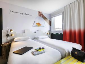 two beds in a hotel room with a sign on the wall at ibis Styles Thonon-les-Bains in Thonon-les-Bains +57 photos