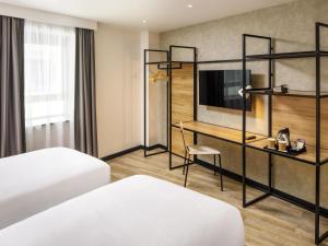 a hotel room with two beds and a desk at ibis London Sutton Point in Sutton