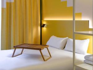 a bedroom with a bed with a wooden table on it at ibis Styles Zurich City Center in Zürich +117 photos