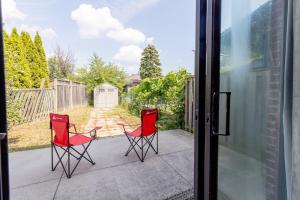 two red chairs sitting on a patio outside a door at Private 2-BR Suite w Patio in Mississauga