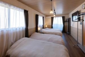 a row of beds in a room with windows at Somnus豊田 ペットOK 最大宿泊人数12名!1棟貸切の宿 in Toyota