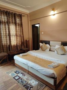 Un dormitorio con dos camas y una gran ventana. en Varuni Gd Hotel Mcleodganj, en McLeod Ganj
