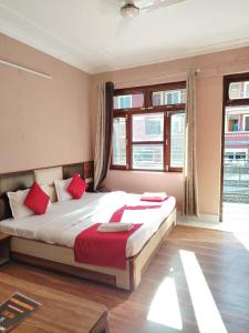 Un dormitorio con una cama grande con almohadas rojas. en Varuni Gd Hotel Mcleodganj, en McLeod Ganj