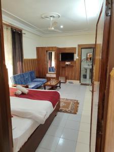 Un dormitorio con una cama grande y un sofá azul en Varuni Gd Hotel Mcleodganj, en McLeod Ganj 22 fotos más