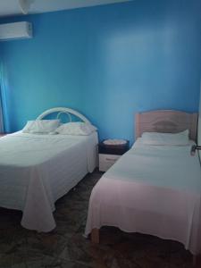 two beds in a room with a blue wall at pousada top mix apt 202 in Florianópolis +17 photos