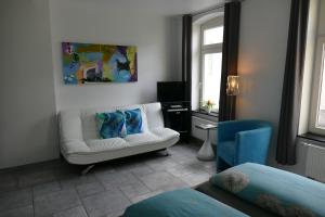 a living room with a white couch and a blue chair at Hotel La Principessa in Hameln