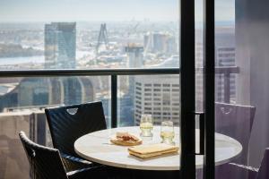 Una mesa con dos vasos y un plato de comida en un balcón. en Meriton Suites Pitt Street, Sydney, en Sídney 83 fotos más