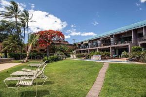 a row of benches sitting in the grass in front of a building at Hoyochi Nikko 201 · HN 201 Relaxing Getaway OceanFront 2BD wPool in Kahana