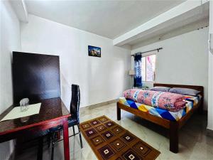 a bedroom with a bed and a table and a desk at Greenview108 in Kurseong