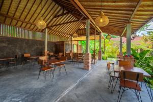restauracja z drewnianymi stołami, krzesłami i światłami w obiekcie Puri Kurnia Ayu w mieście Ubud