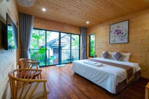 a bedroom with a bed and a large window at San Signature - Suối Ngọc Retreat in Tien Xuan +119 photos
