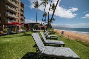 a row of white benches sitting on the beach at Nani Kai Hale 605 · NKH 605 Remodeled BeachFront w Pool AC Sandy in Kihei