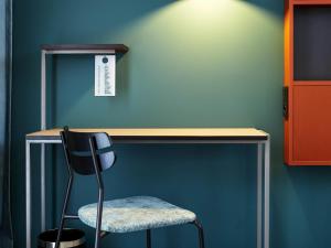 a desk with a chair next to a green wall at ibis Styles Kraków Centrum in Kraków