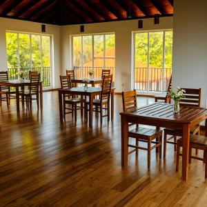 a dining room with tables and chairs and windows at Pearl Paradise Villa in Awariwatta