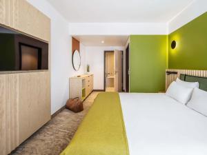 a bedroom with a white bed and a green wall at Mercure Katowice Centrum in Katowice