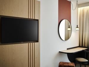 a flat screen tv hanging on a wall with a mirror at Mercure Katowice Centrum in Katowice +100 photos