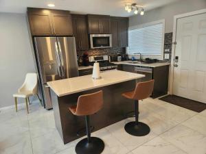 a kitchen with a counter and two bar stools at Modern Family Home with guest heat garage, Pet-Friendly!- NO BASEMENT in Edmonton