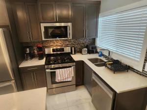 a kitchen with a stove and a sink and a microwave at Modern Family Home with guest heat garage, Pet-Friendly!- NO BASEMENT in Edmonton