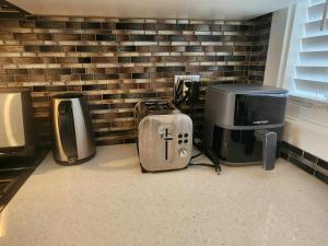a room with a brick wall with a tv and other appliances at Modern Family Home with guest heat garage, Pet-Friendly!- NO BASEMENT in Edmonton