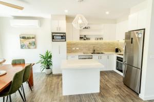 a kitchen with white cabinets and a wooden table at Amber Mist Villa - Two in Bright