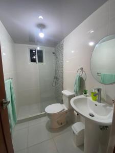 a white bathroom with a toilet and a sink at Cozy 3br apartment near to airport & beaches in La Cana