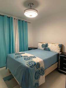 a bedroom with a bed with blue sheets and blue curtains at Cozy 3br apartment near to airport & beaches in La Cana