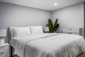 Un dormitorio blanco con una cama blanca y una planta en The Hideaway Suite, en Bellerose Terrace