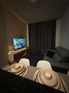 a room with a table and chairs and a television at Apartamento moderno na praia da palhoça c garagem in Palhoça +27 photos