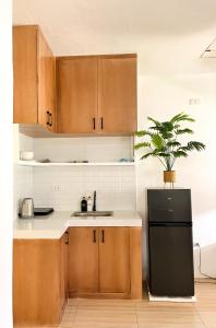 une cuisine avec des armoires en bois et un réfrigérateur noir dans l'établissement Zand Pointe Suites, à General Luna