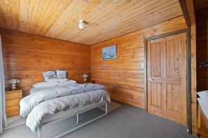 a bedroom with a bed and a wooden wall at Neptune's Nook in Cape Paterson