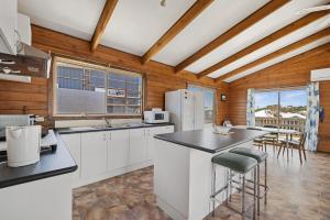 a kitchen with white appliances and wooden walls at Neptune's Nook in Cape Paterson +6 photos