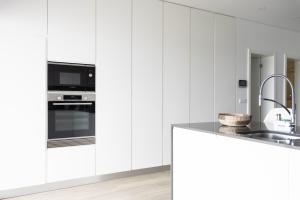 a white kitchen with a sink and a microwave at Casa Pedra de Sal in Ribeira Grande